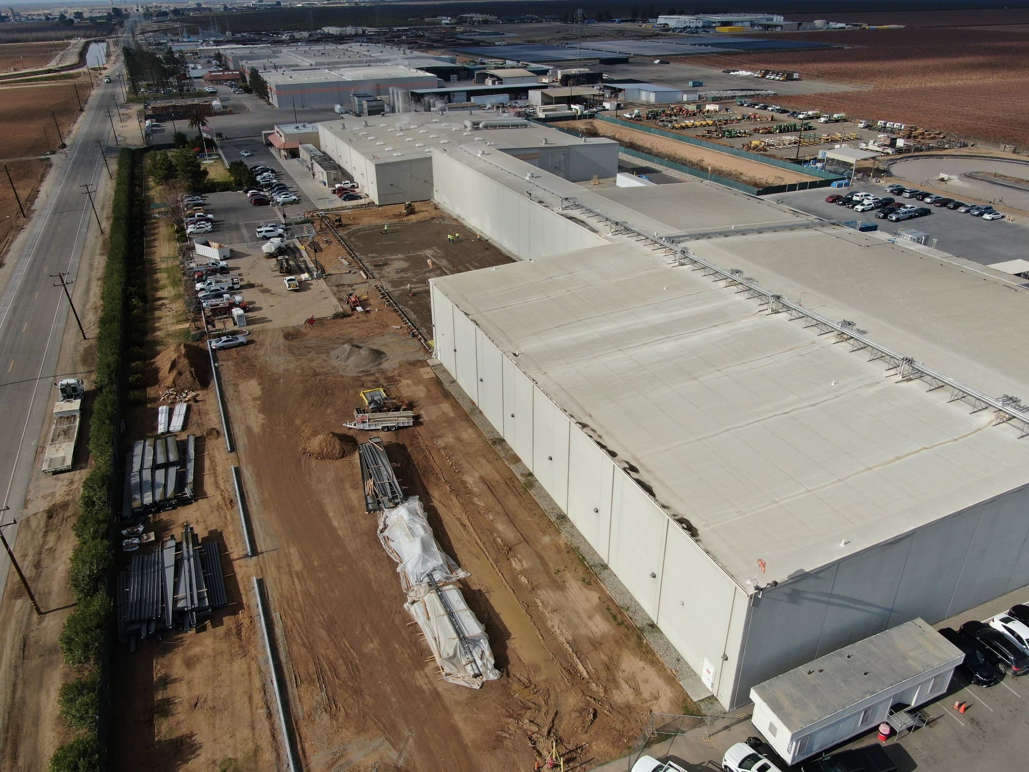 The Califia Farms plant under construction in Bakersfield, tilt-up panels erected and pipe staged on the pad