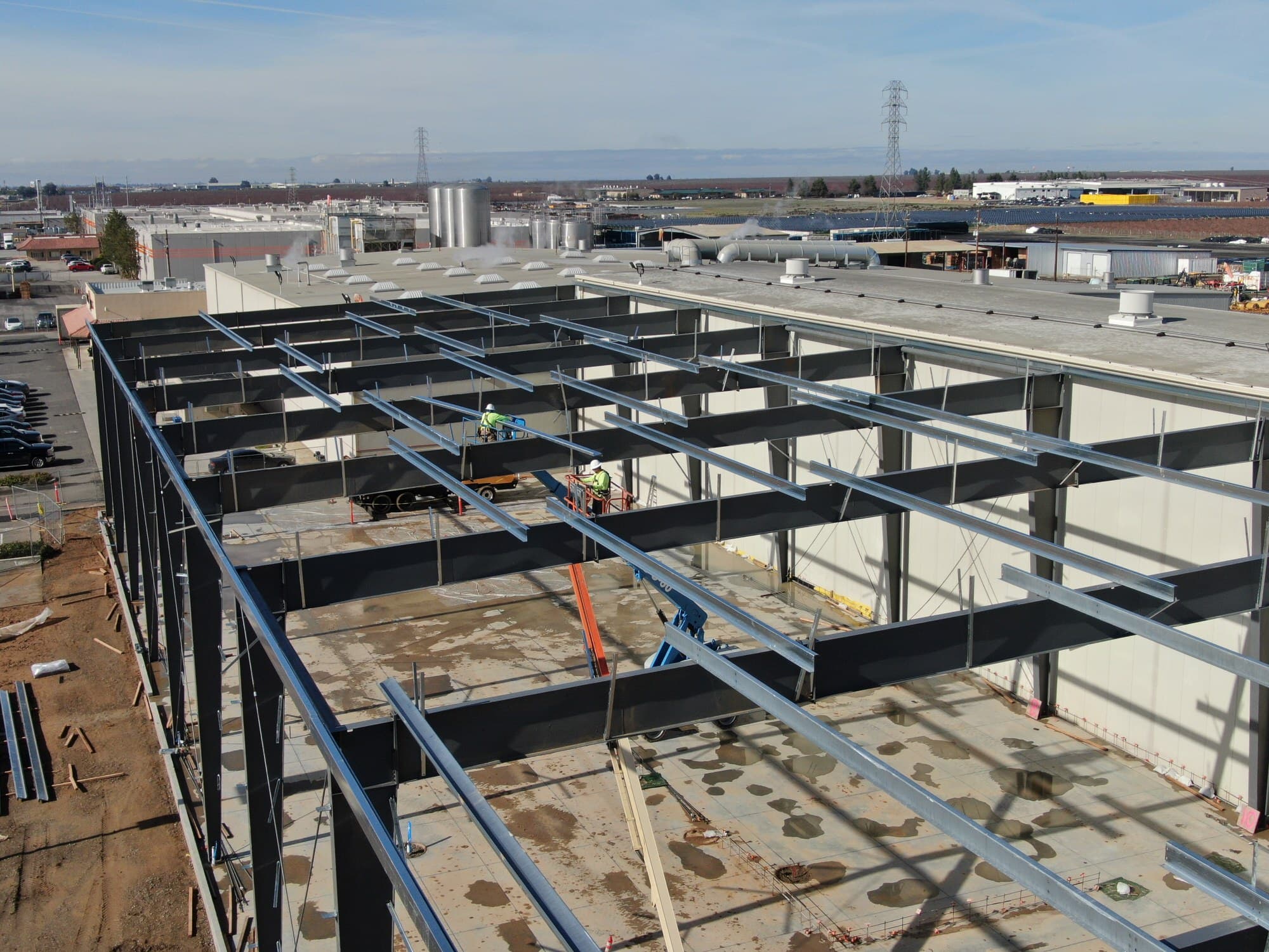 Structural steel framing going up over the deck at Califia Farms, with the crew setting beams