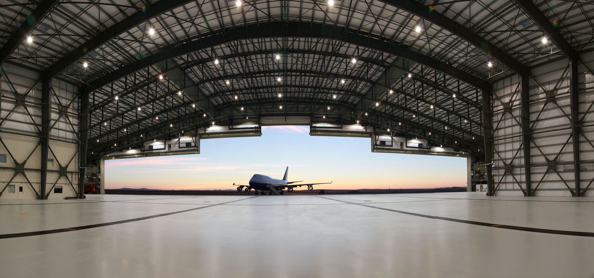 The Stratolaunch carrier aircraft inside its hangar at dusk, framed by the open Mega Door