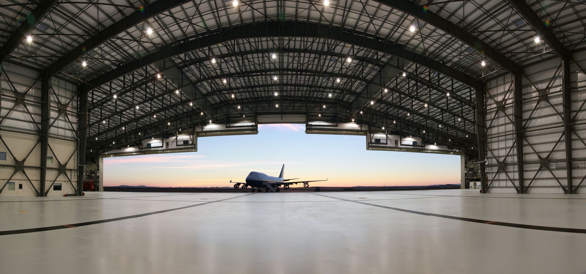 The Stratolaunch carrier aircraft inside its hangar at dusk, framed by the open Mega Door